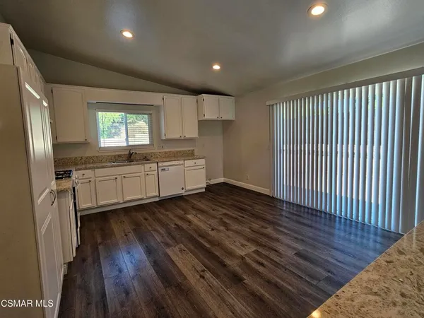 a kitchen with granite countertop a stove a sink and a refrigerator
