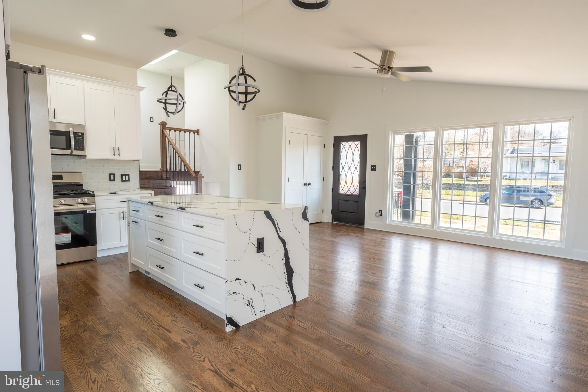 13208 Holdridge Road Silver Spring, MD 20906 - Photo 6 of 29 a large white kitchen with kitchen island a stove a refrigerator a oven and a large island with wooden floor
