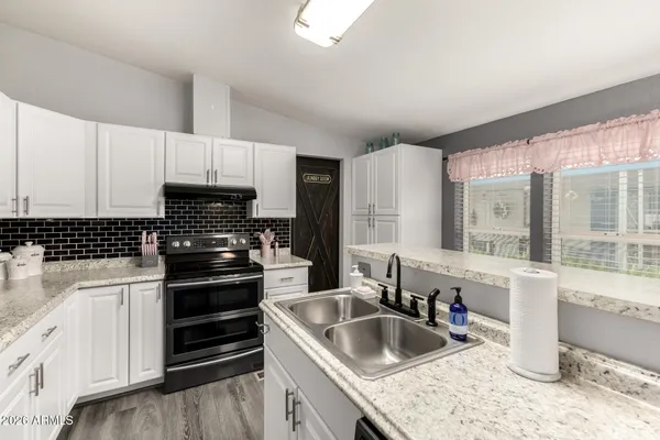 a kitchen with granite countertop a sink stove and cabinets