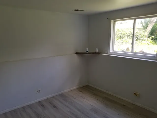 a view of a small space with wooden floor and a window