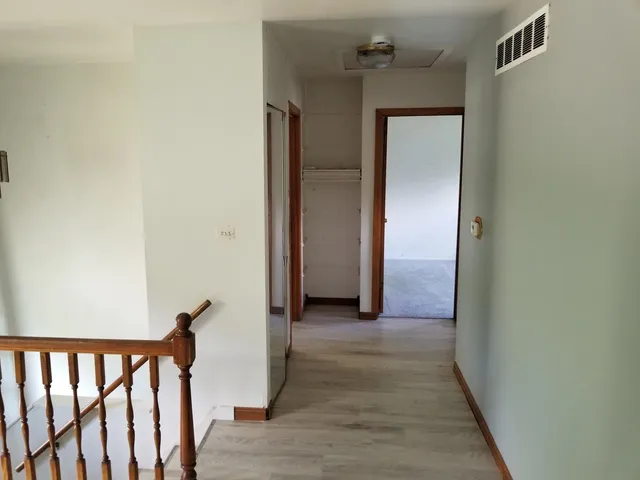 a view of a hallway with wooden floor and staircase