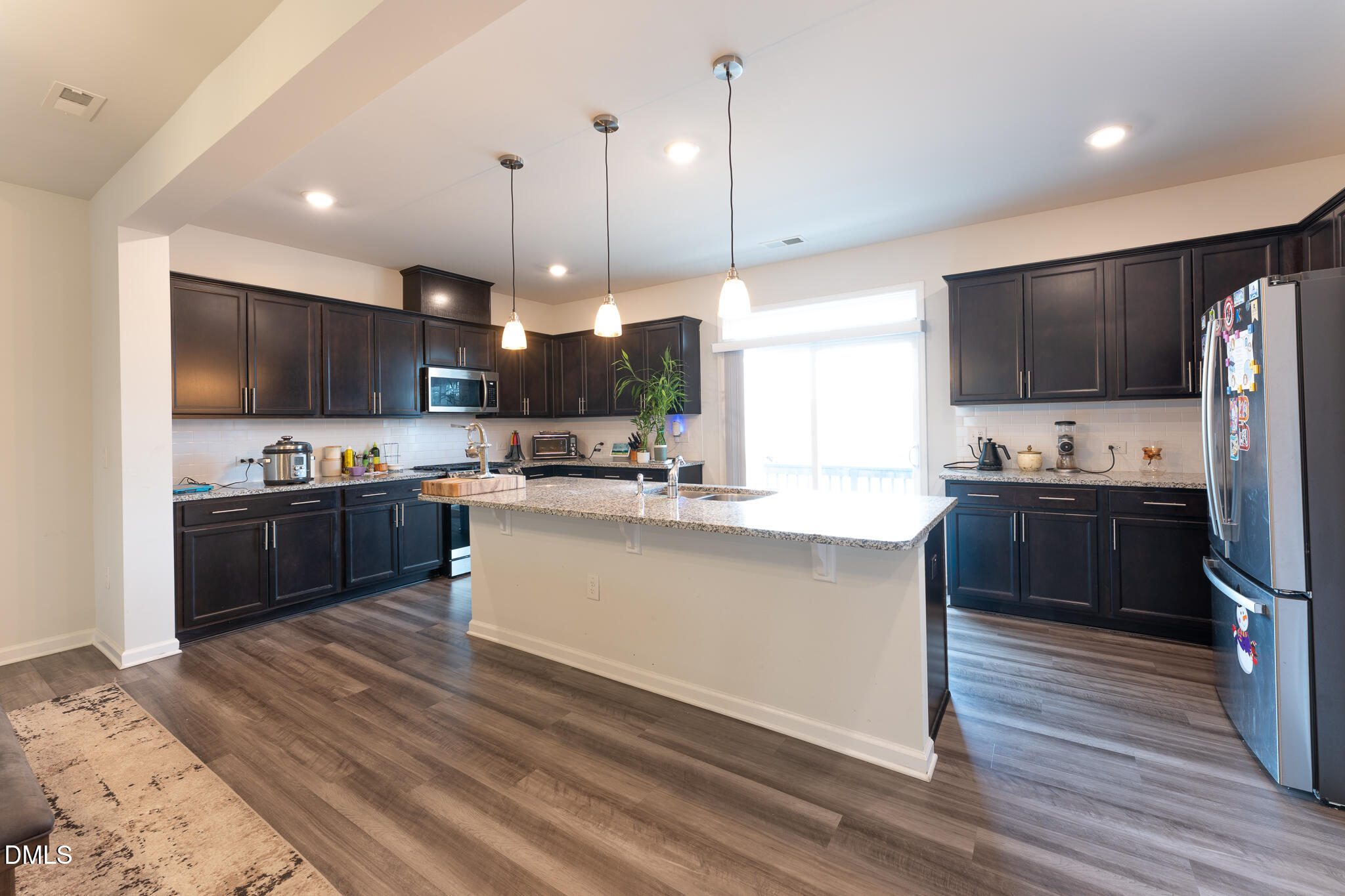1296 Barn Cat Way Apex, NC 27502 - Photo 6 of 22 a kitchen with kitchen island a refrigerator a stove a microwave oven a sink with island and chairs