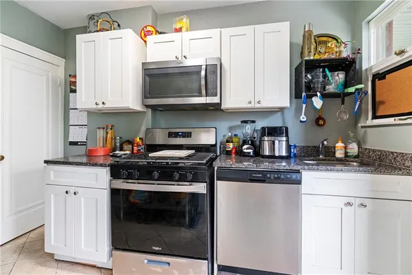 a kitchen with stainless steel appliances granite countertop a stove top oven a refrigerator a sink and dishwasher with white cabinets