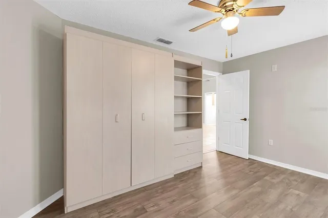 an empty room with wooden floor fan and windows