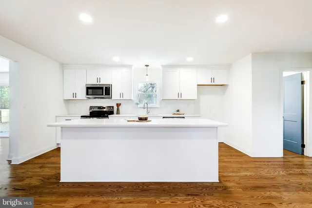 a kitchen with stainless steel appliances a sink a stove a microwave a center island and cabinets