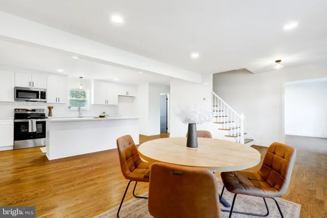 a kitchen with stainless steel appliances kitchen island granite countertop a dining table chairs and a refrigerator