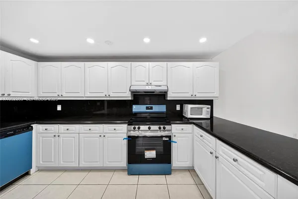 a view of a refrigerator in kitchen and an empty room