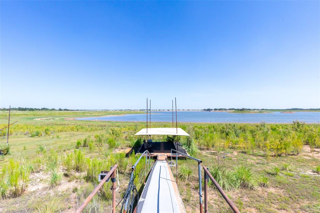 659 Rocky Point Road Blackwell, TX 79506 - Photo 36 of 40 Dock structure with covered boat slip, featuring a walkway with handrails and expansive waterfront