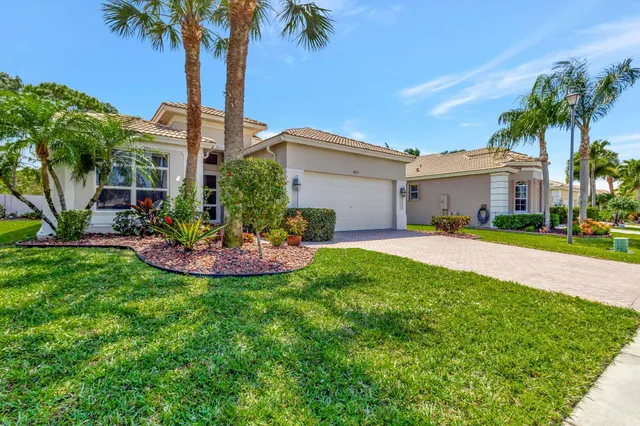 a view of a house with a yard and palm trees