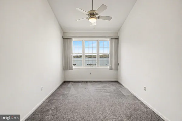an empty room with windows and ceiling fan