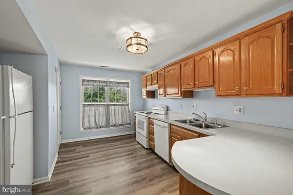 a kitchen with stainless steel appliances granite countertop a stove a sink dishwasher and a refrigerator with wooden floor