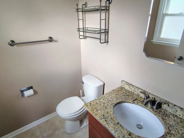 a bathroom with a granite countertop toilet sink and mirror
