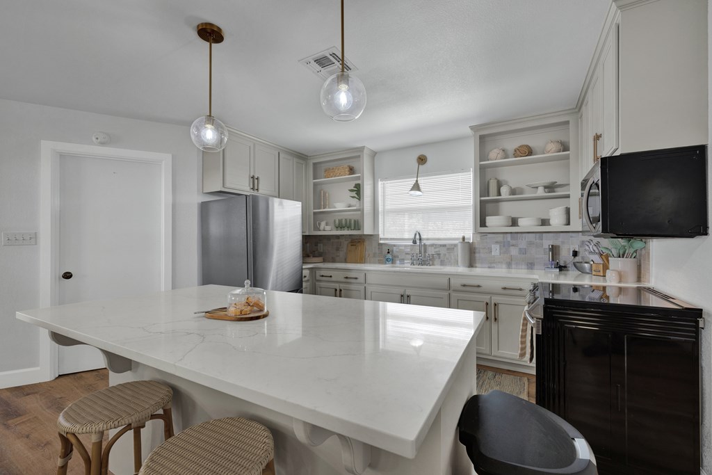 113 Weitz Road Fredericksburg, TX 78624 - Photo 39 of 50 a kitchen with stainless steel appliances granite countertop a sink a stove a refrigerator and chairs