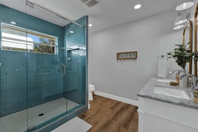 a bathroom with a granite countertop sink a mirror and shower