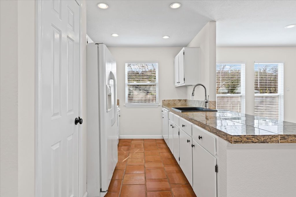 303 Fantail Loop, Unit A Austin, TX 78734 - Photo 12 of 28 a kitchen with granite countertop a sink stainless steel appliances white cabinets and a window
