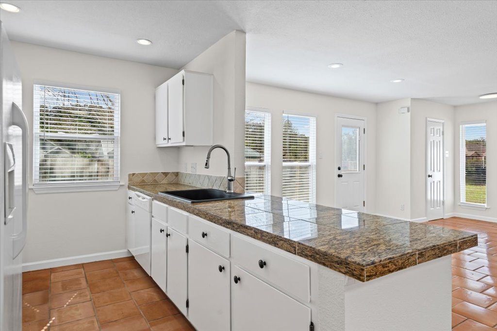 303 Fantail Loop, Unit A Austin, TX 78734 - Photo 13 of 28 a kitchen with granite countertop a sink and white cabinets