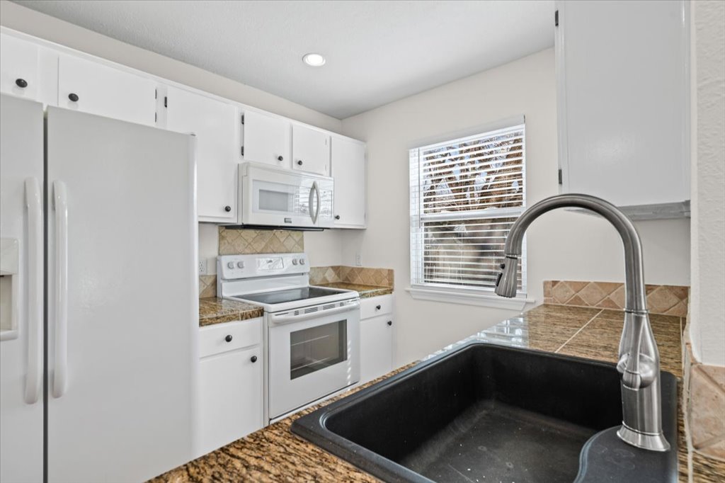 303 Fantail Loop, Unit A Austin, TX 78734 - Photo 14 of 28 a kitchen with stainless steel appliances granite countertop a stove a sink and a microwave