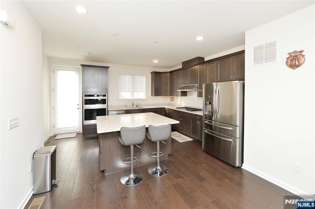 12-48 Plaza Road Fair Lawn, NJ 07410 - Photo 6 of 26 a kitchen with stainless steel appliances kitchen island granite countertop a refrigerator a stove a sink dishwasher and white cabinets with wooden floor