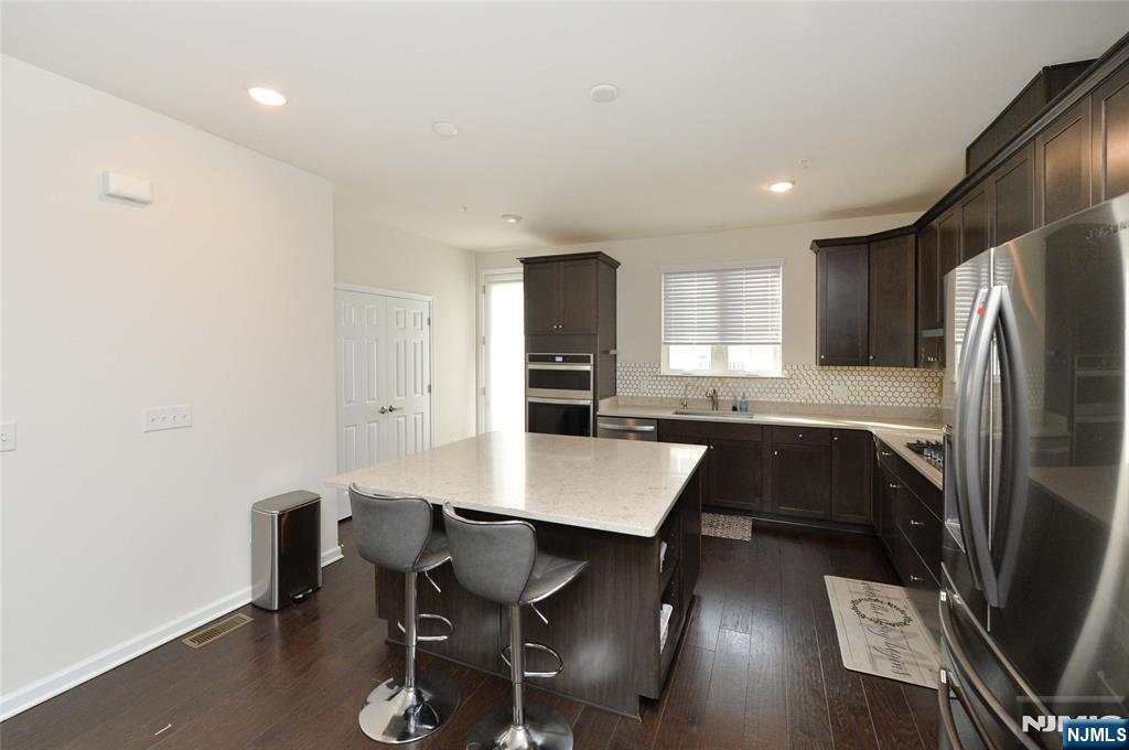 12-48 Plaza Road Fair Lawn, NJ 07410 - Photo 8 of 26 a kitchen with a table chairs refrigerator and microwave