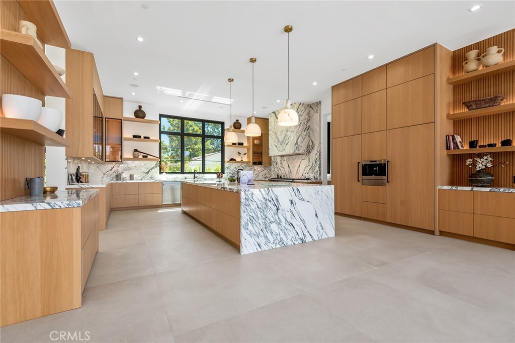 23650 Long Valley Road Hidden Hills, CA 91302 - Photo 12 of 57 a large white kitchen with kitchen island a large counter top and stainless steel appliances