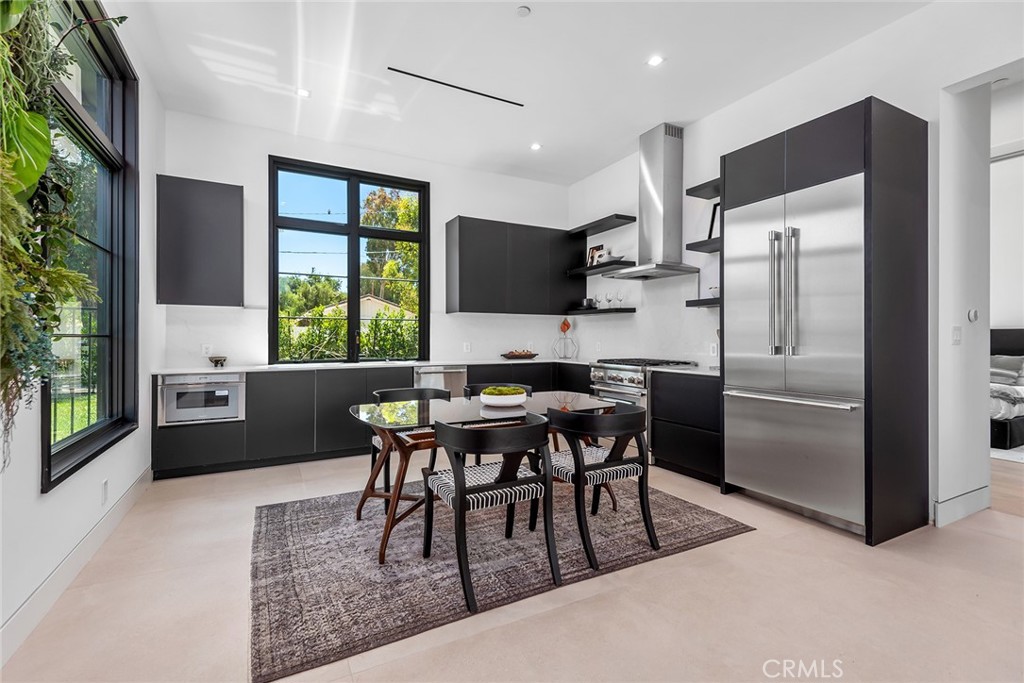 23650 Long Valley Road Hidden Hills, CA 91302 - Photo 47 of 57 a kitchen with stainless steel appliances granite countertop a table chairs sink refrigerator and microwave