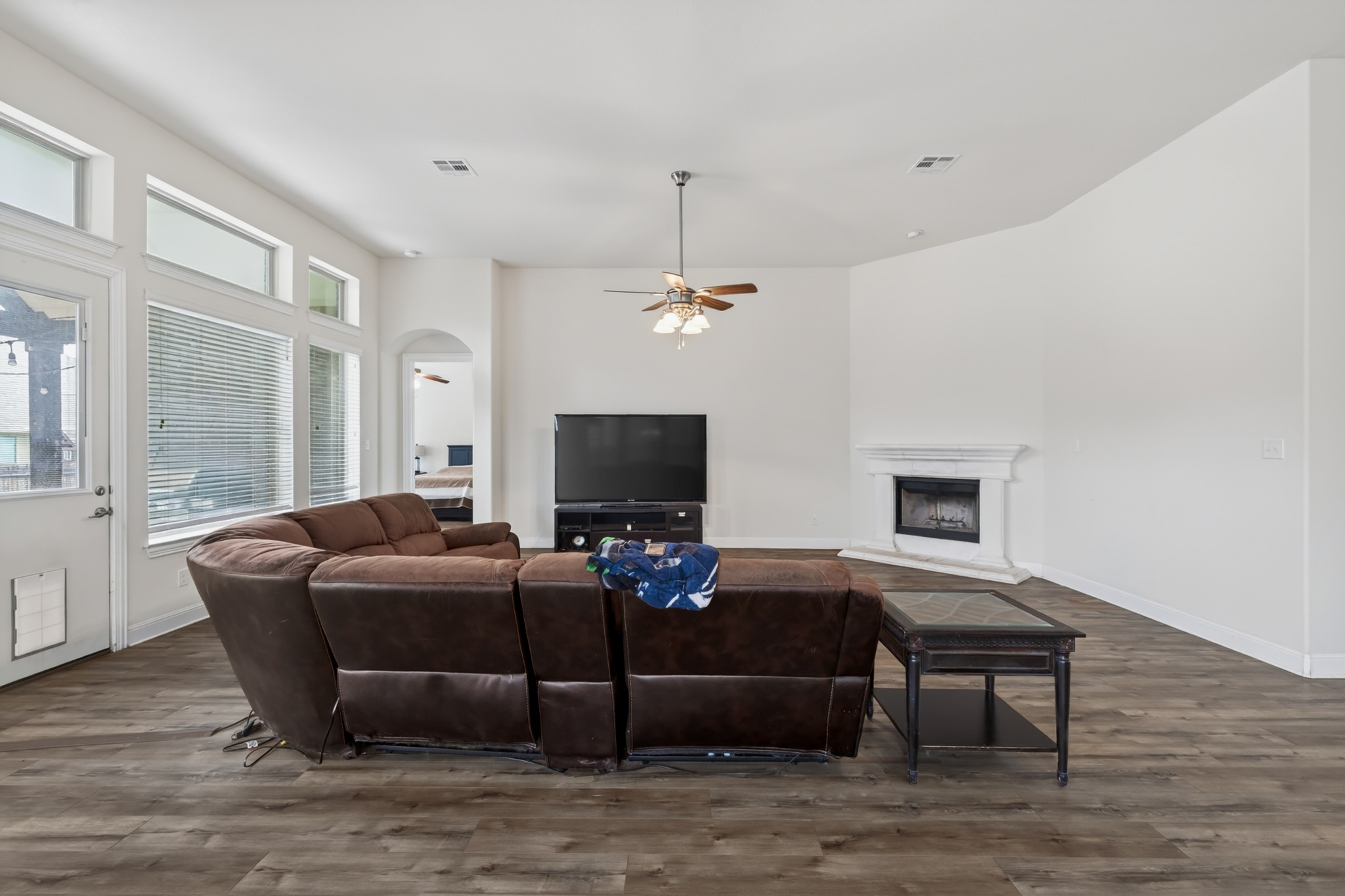 1017 Tabernash Leander, TX 78641 - Photo 15 of 38 Spacious living area featuring wood-finish flooring, a corner fireplace with a white mantel, and ample natural light from multiple windows