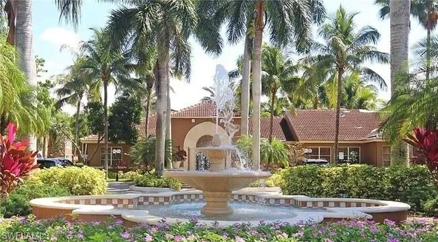 a front view of a house with garden and fountain