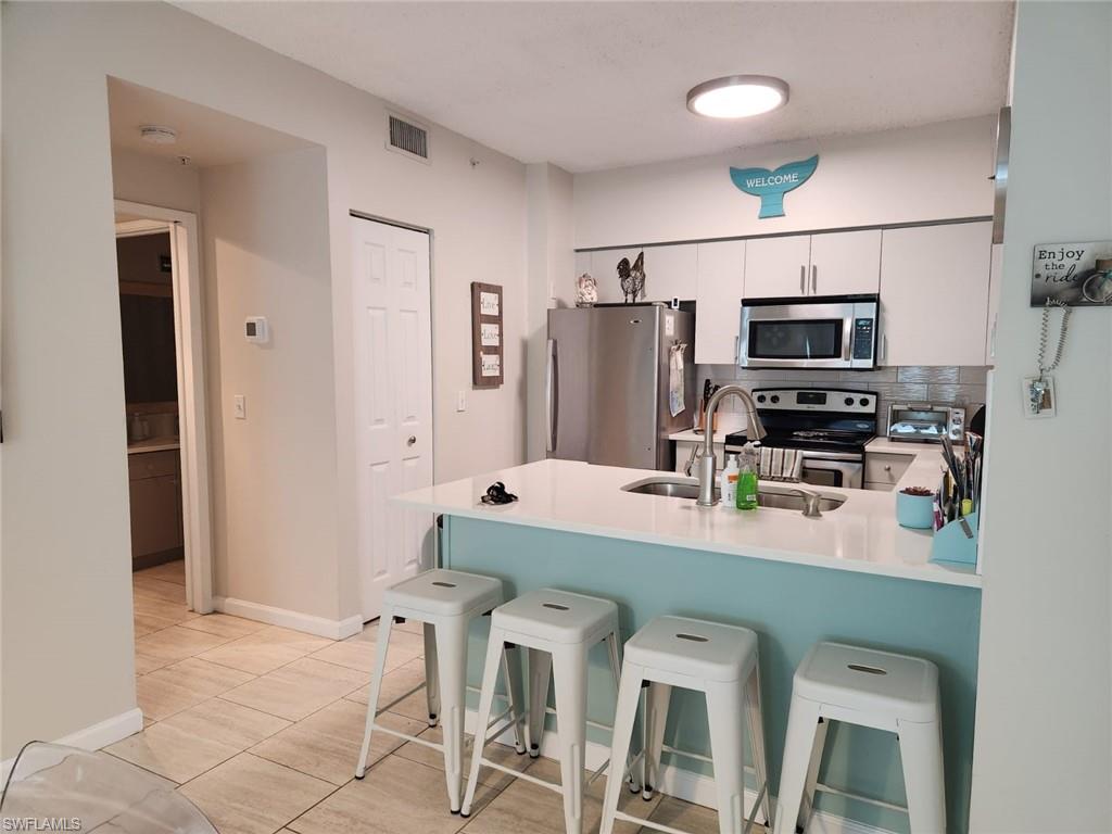 1200 Reserve Way, Unit 201 Naples, FL 34105 - Photo 3 of 20 a kitchen with stainless steel appliances a refrigerator stove microwave and cabinets