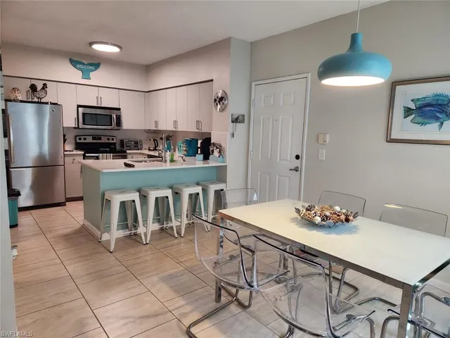 a kitchen with stainless steel appliances kitchen island granite countertop a table chairs and a refrigerator