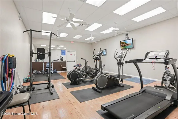 a room with gym equipment and wooden floor