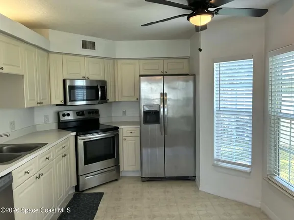 a kitchen with stainless steel appliances granite countertop a refrigerator a sink a stove top oven a chimney and a window