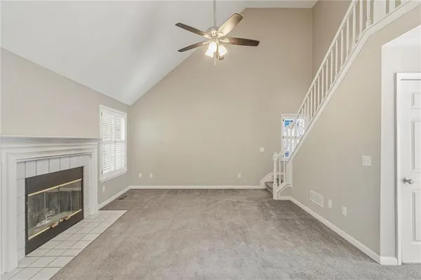 a view of an empty room with chandelier fan and fire place