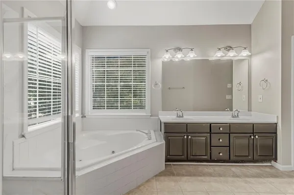 a spacious bathroom with a tub sink and mirror