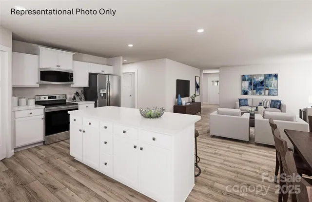 a large white room with kitchen island a flat screen tv and a couch