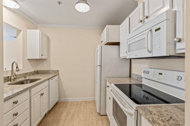 a kitchen with granite countertop a sink a stove and cabinets