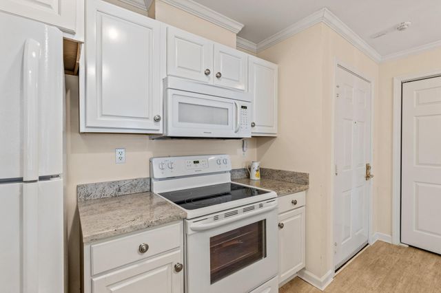 a kitchen with granite countertop white cabinets and white appliances