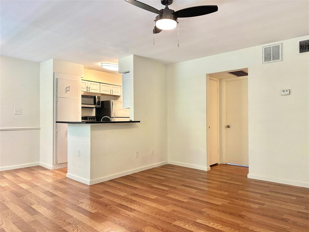 a view of a kitchen with wooden floor and a ceiling fan