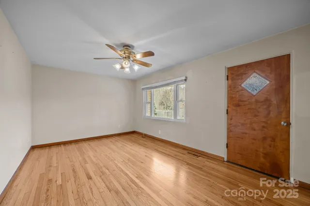 a view of an empty room with wooden floor and a window