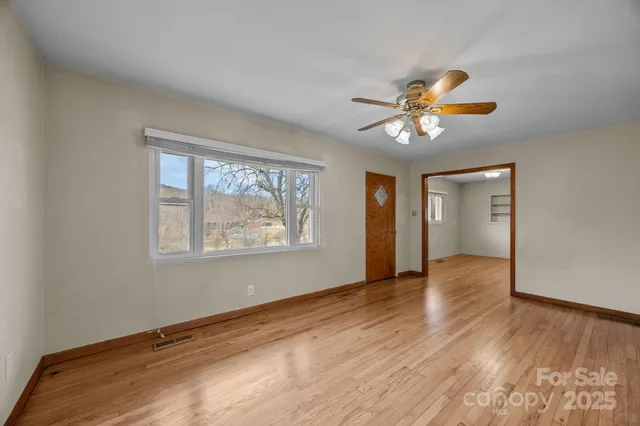 a view of an empty room with window and wooden floor