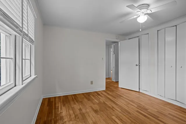 a view of empty room with wooden floor and fan