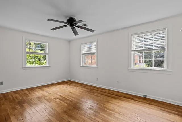 a view of empty room with wooden floor and fan