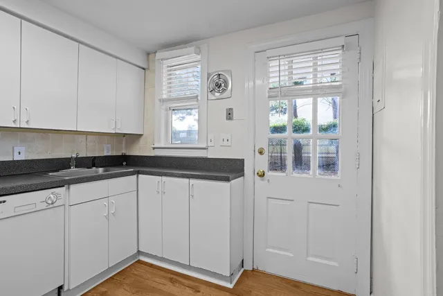 a kitchen with granite countertop white cabinets and window
