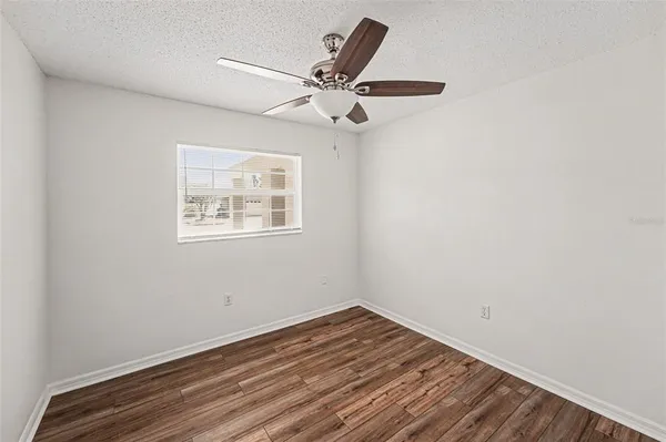 an empty room with wooden floor a ceiling fan and window