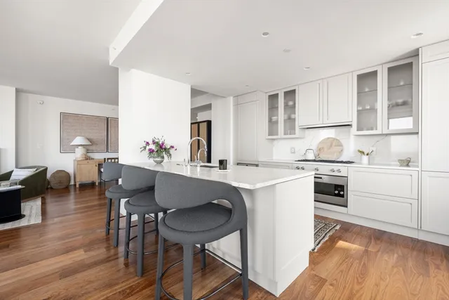 a kitchen with a table chairs a sink dishwasher stove and cabinets with wooden floor