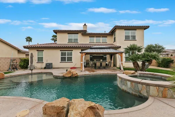 a view of a house with backyard sitting area and swimming pool