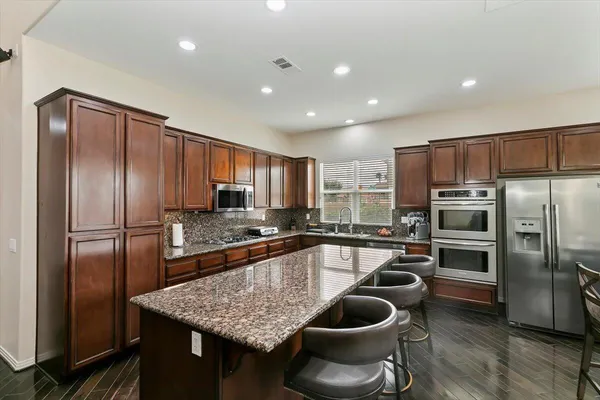 a kitchen with stainless steel appliances granite countertop a sink refrigerator and cabinets