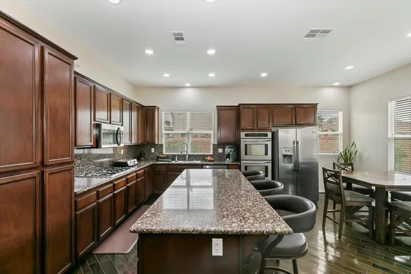 a kitchen with stainless steel appliances granite countertop table chairs and a refrigerator