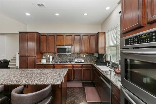 a kitchen with kitchen island granite countertop a sink stainless steel appliances and cabinets