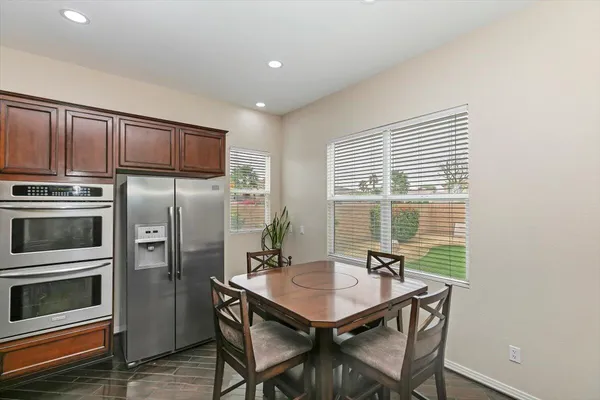 a kitchen with stainless steel appliances a dining table chairs and refrigerator