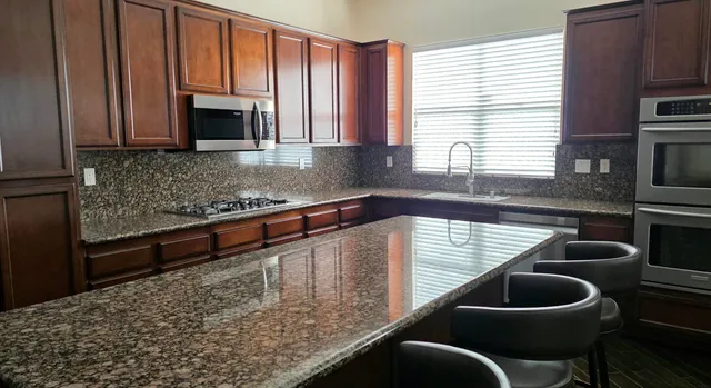a kitchen with granite countertop a stove a sink and a microwave